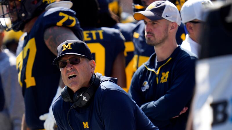 Michigan head coach Jim Harbaugh, front left, watches against Rutgers as analytics assistant...